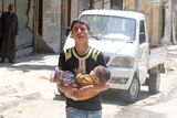 A young man carries a baby from a site hit by airstrikes in Aleppo.