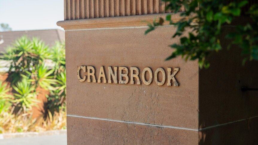 The word Cranbrook in gold on a sandstone column at the gates of a school.