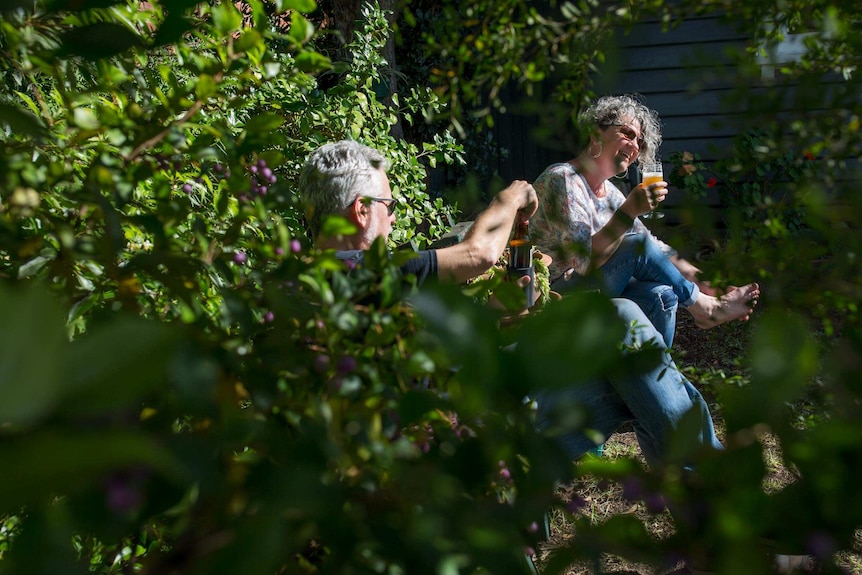 Xenia and Paul relax with a beer in a sunny patch of their front garden.
