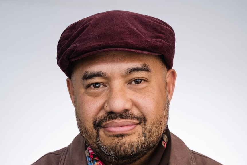 A man of Tongan-Australian descenet wearing a burgundy beret with slight facial hair and nose ring