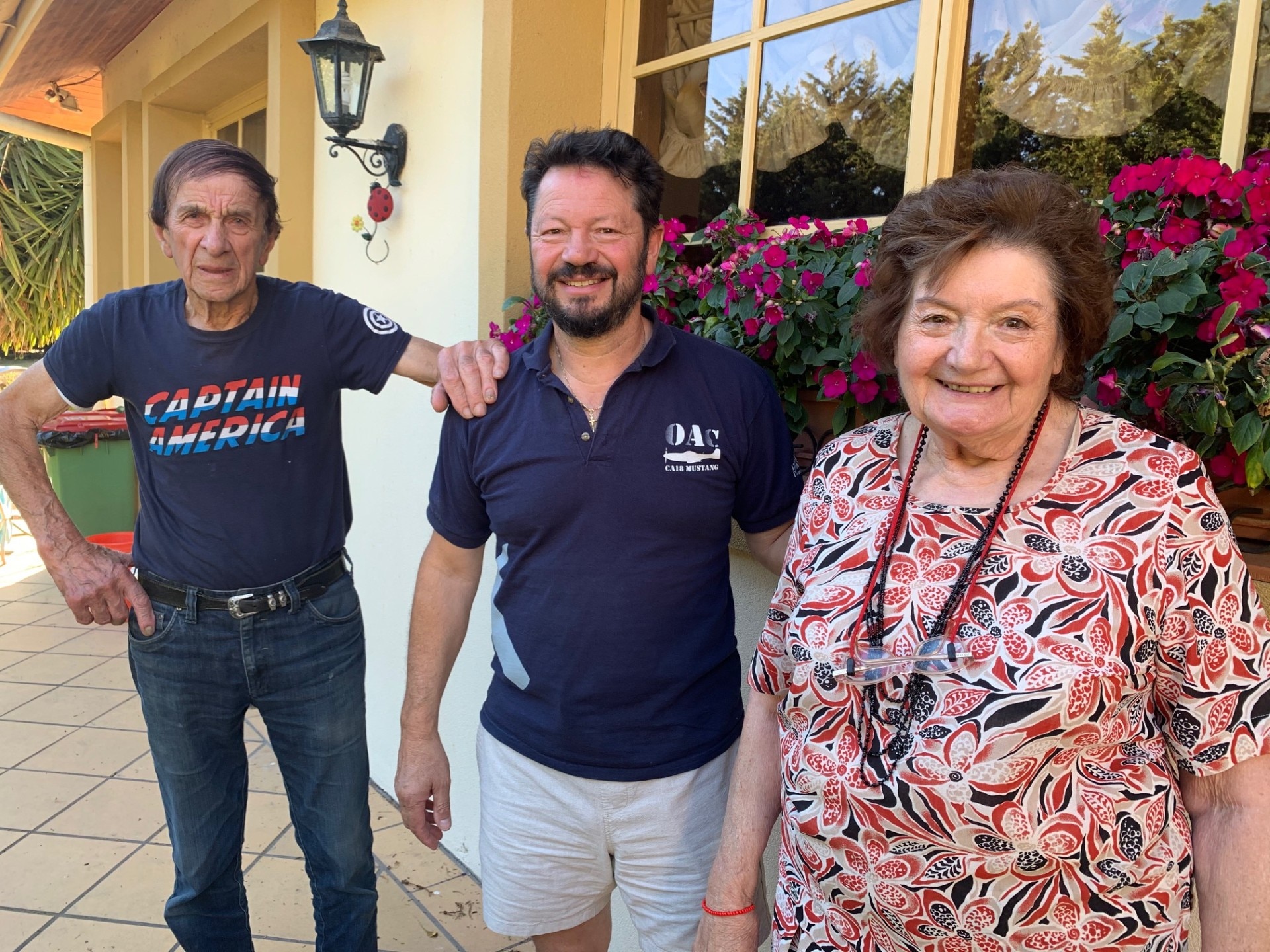 Un hombre mayor que llevaba una camiseta del Capitán América junto con un hombre y una mujer más jóvenes que llevaban un top floral.
