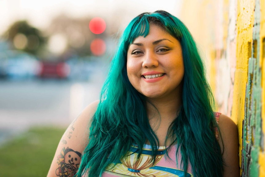 A woman with green hair smiles broadly.