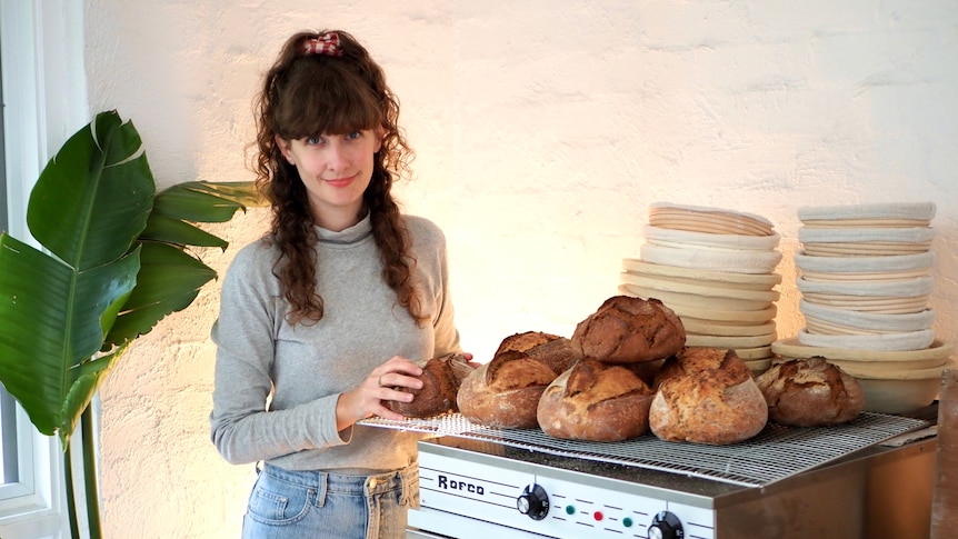 Mary Grace Quigley stands with loaves of sourdough bread in her kitchen.