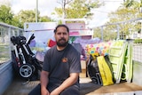 A man sitting on the edge of a trailer full of furniture.