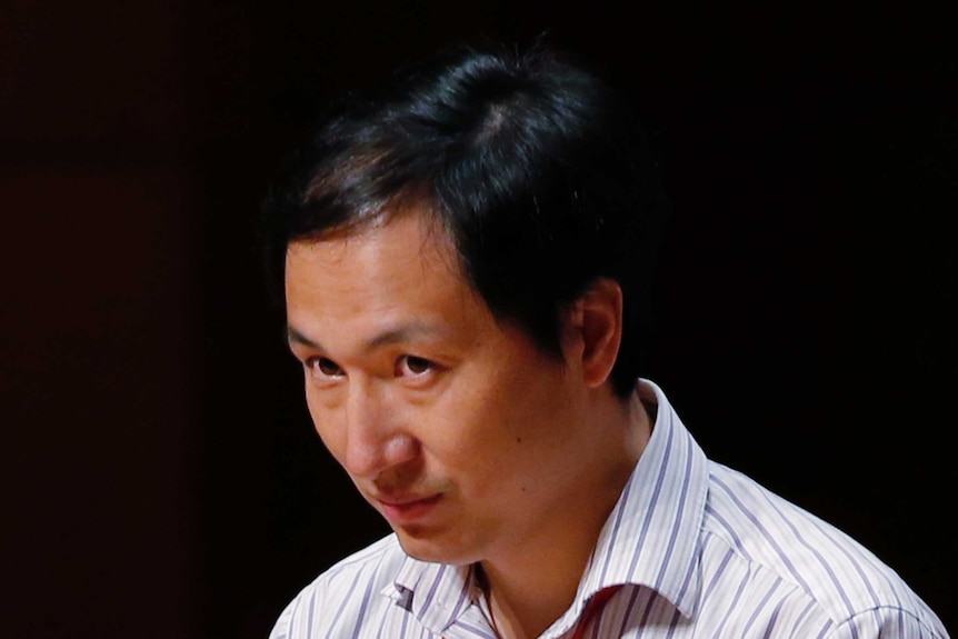 Disgraced Chinese scientist He Jiankui pictured onstage against black backdrop