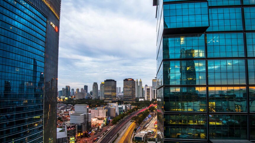 From a high vantage point, you look down on a freeway running through blue-tinted high-rises in Jakarta.