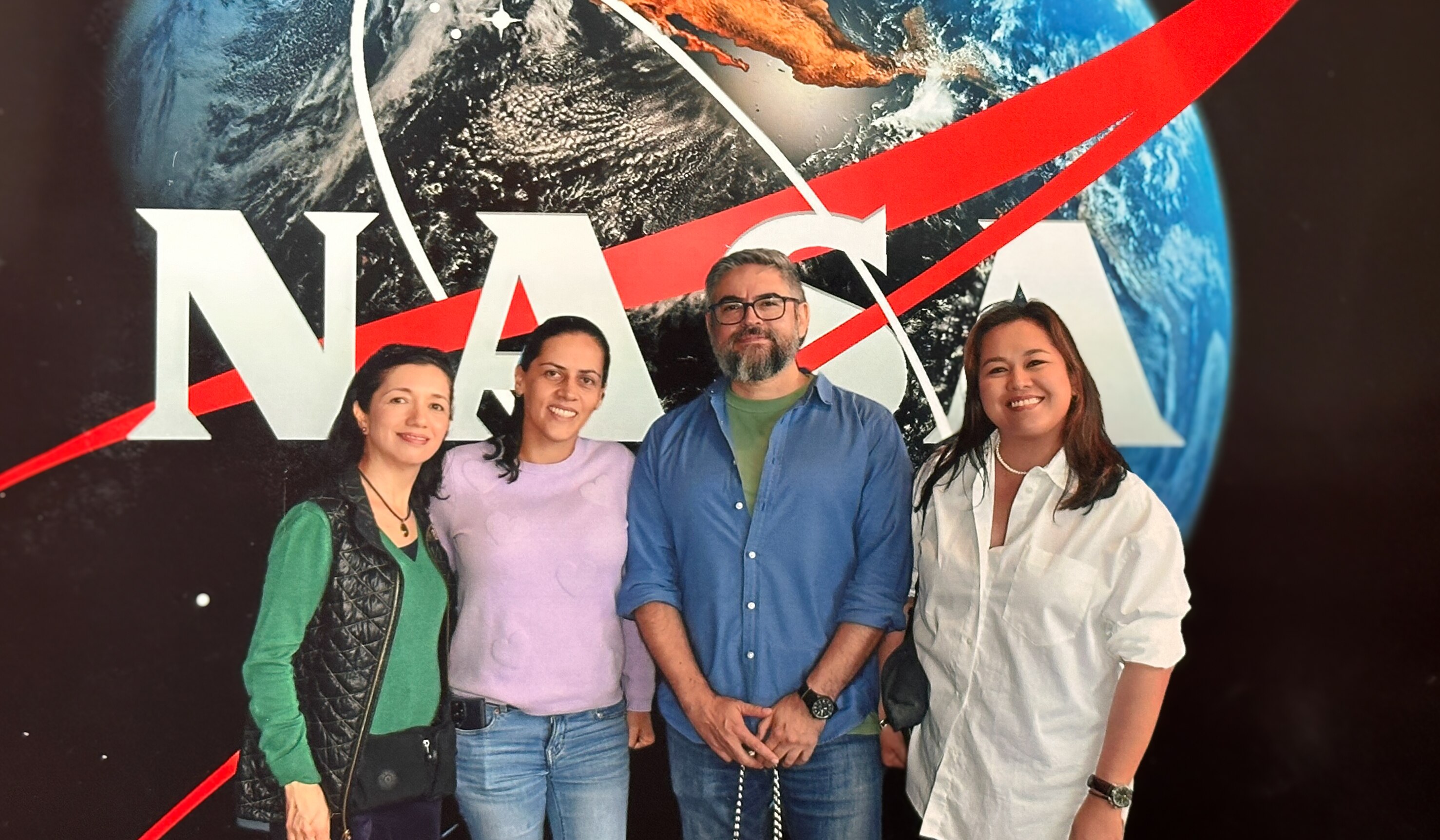 Three women and a man standing in front of a NASA sign