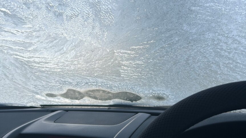 image from inside car from drivers seat of ice covering a windscreen