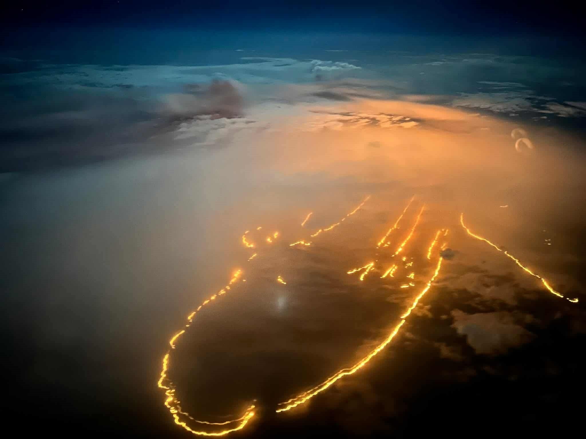 Lines of fire seen from above, with clouds and the night sky