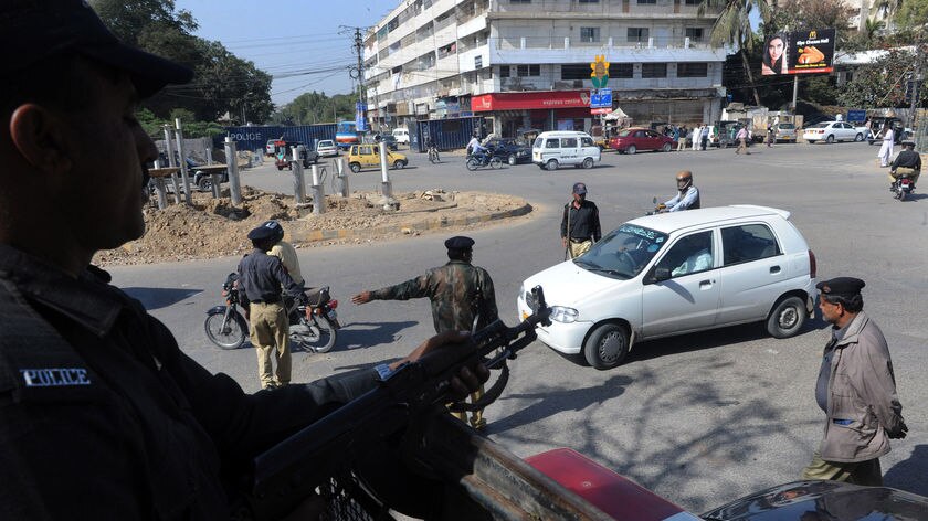 Pakistani policemen stand guard at a security check point in Karachi