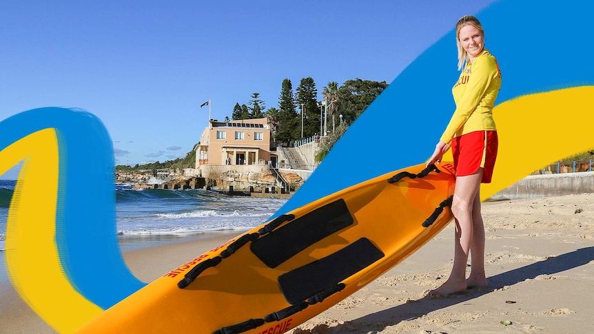 Young female surf lifesaver holding a rescue board on beach with Coogee Surf Life Saving Club in the background.