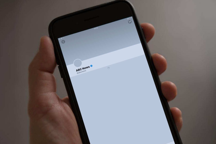 手握手机，荧幕上显示澳广新闻ABC News的推特账户无法打开。