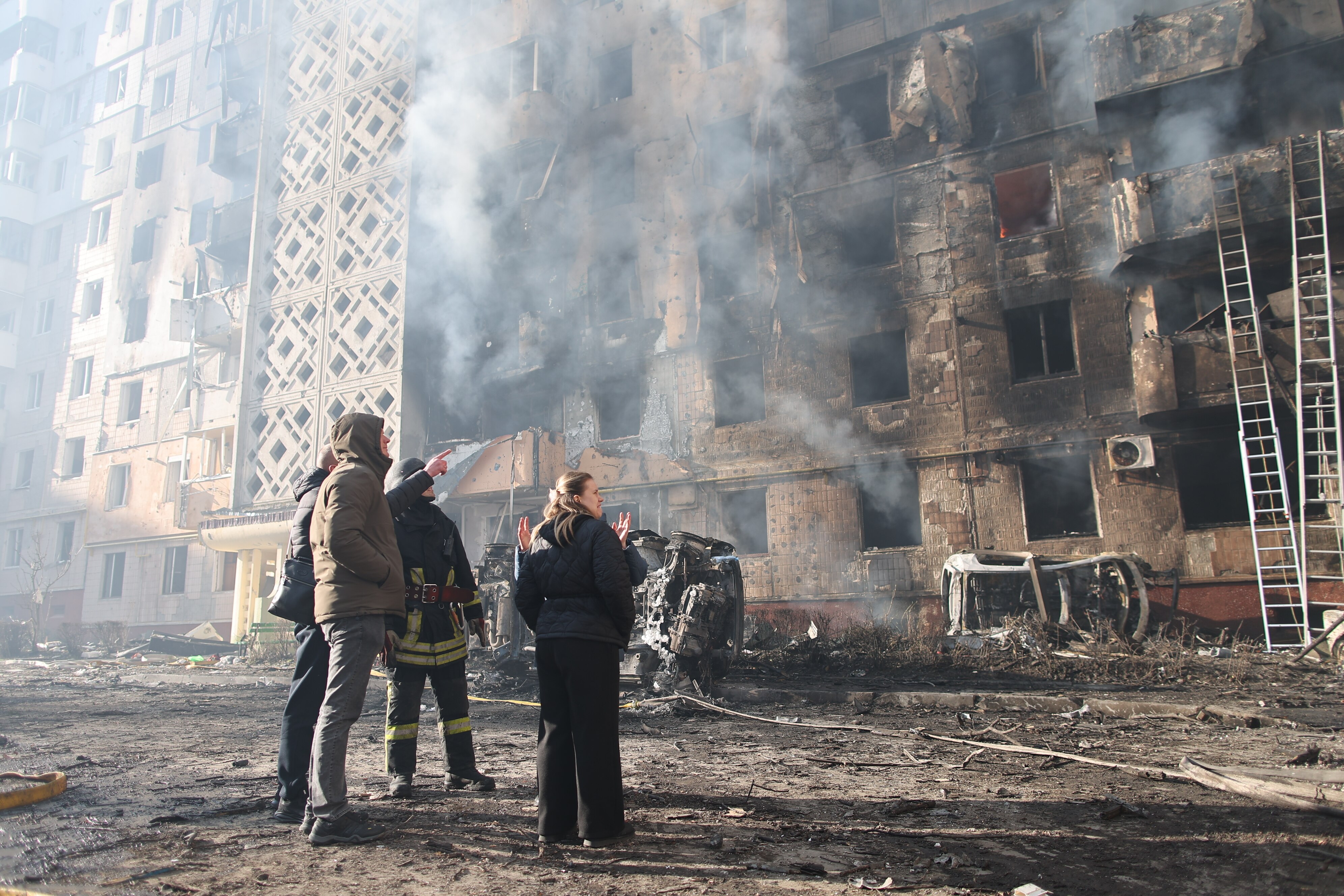 People look at a residential building which was heavily damaged