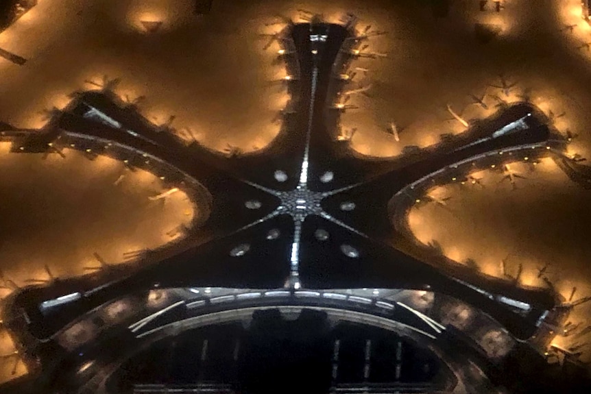 An aerial shot of Beijing's new airport shows a starfish-like structure lit up.