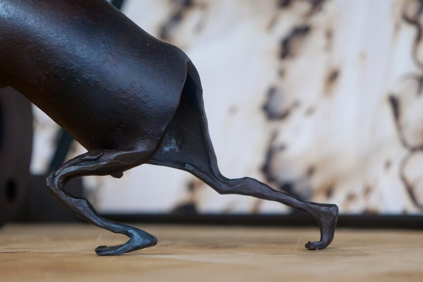 A sculpture made out of pipe with small legs on the end. 