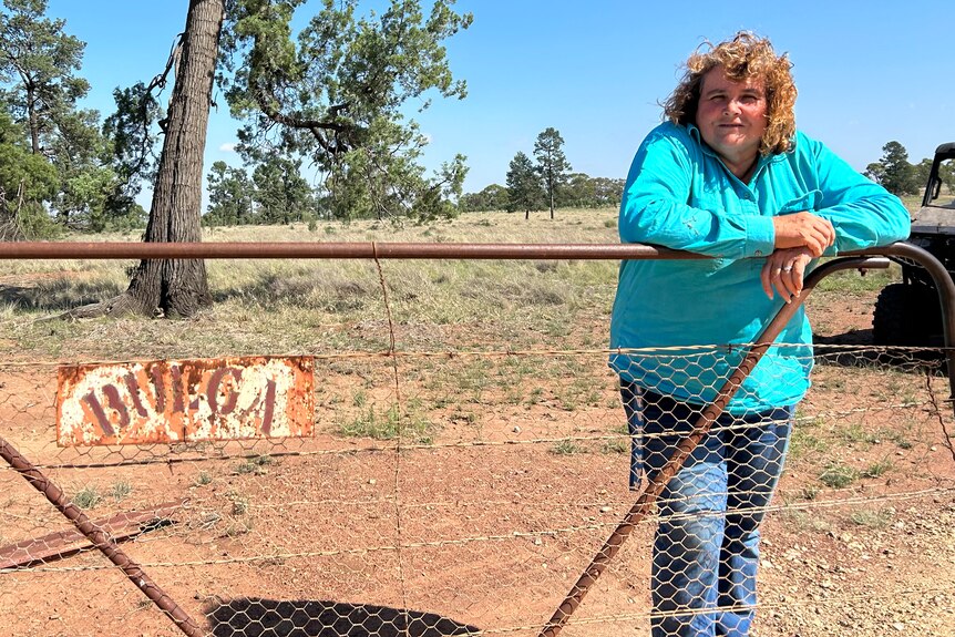 Photo of woman standing at front gate of property. 