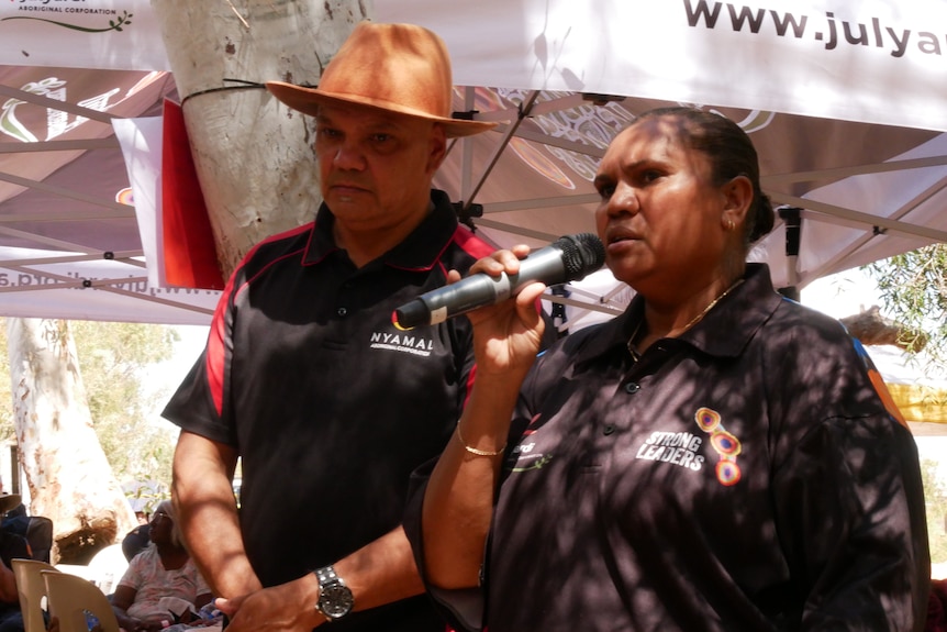 A man and a woman holding a microphone speaking.