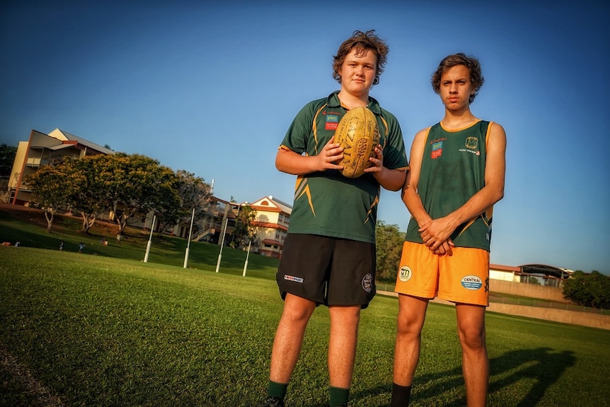 The pair stand on a football oval