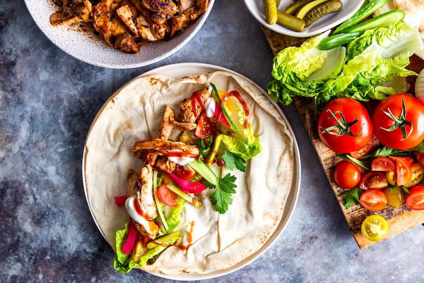Chicken shawarma in a Lebanese wrap with pickles, lettuce, tomatoes and garlic sauce, a fast and filling family meal.
