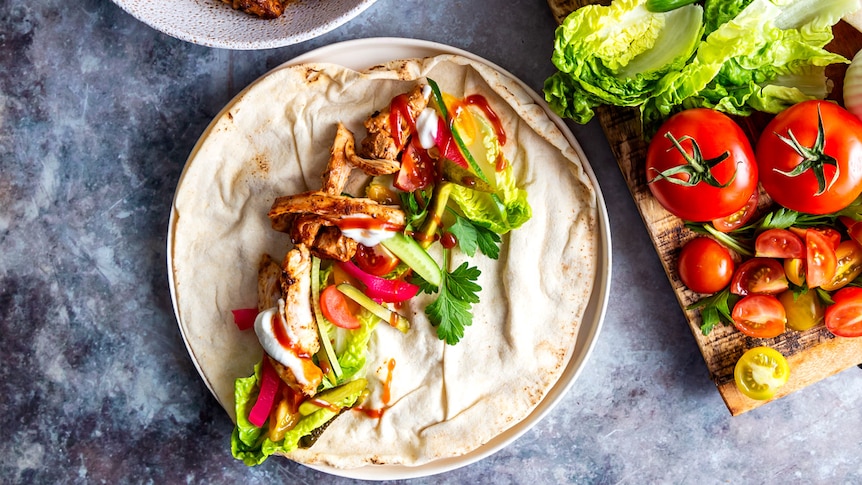 Chicken shawarma in a Lebanese wrap with pickles, lettuce, tomatoes and garlic sauce, a fast and filling family meal.