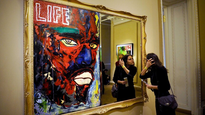 A woman looks at the painting Back by Sylvester Stallone.