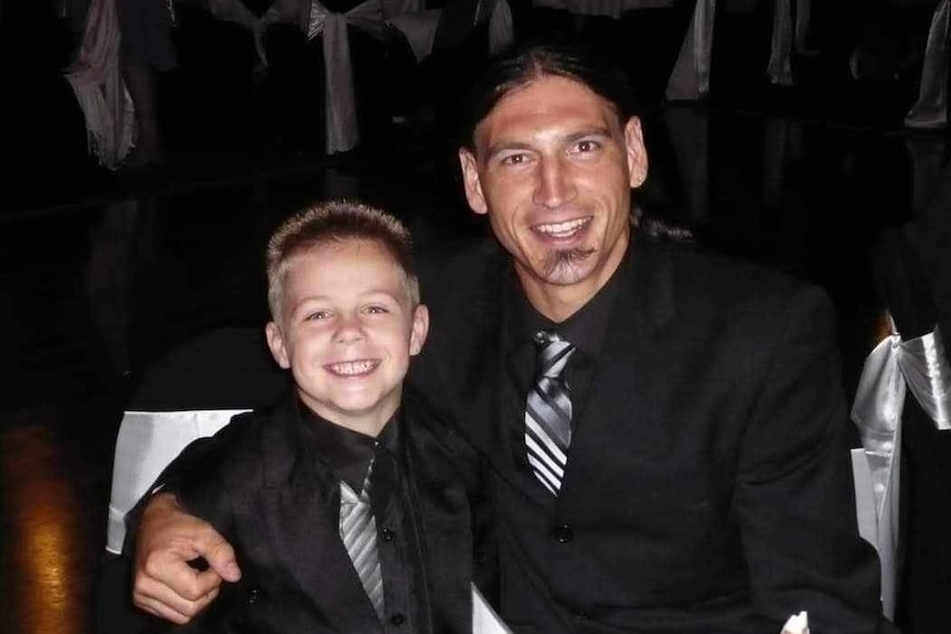 A smiling blonde child and his father in a suit