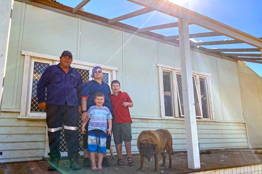 Warren and Tammy Treasure with their children Liam and Nate, standing on the verandah of their family home. 