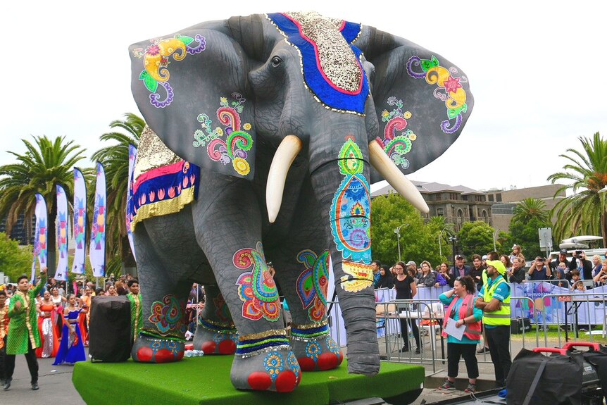 Dancers in the Moomba parade trail a float of a giant elephant.