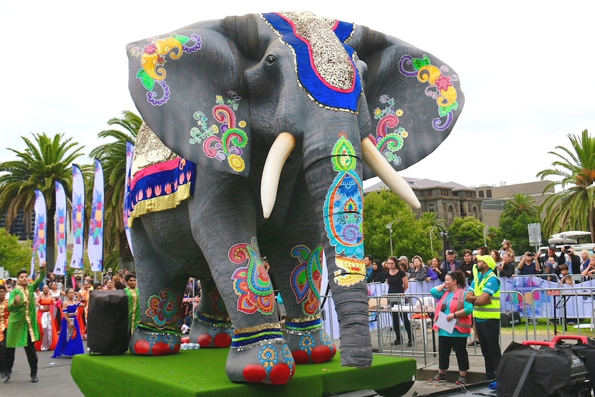 Dancers in the Moomba parade trail a float of a giant elephant.