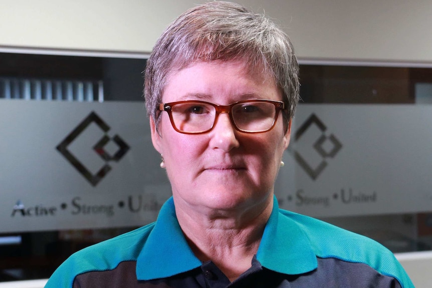 Australian Services Union WA assistant branch secretary Jill Hugo stands in front of a wall.