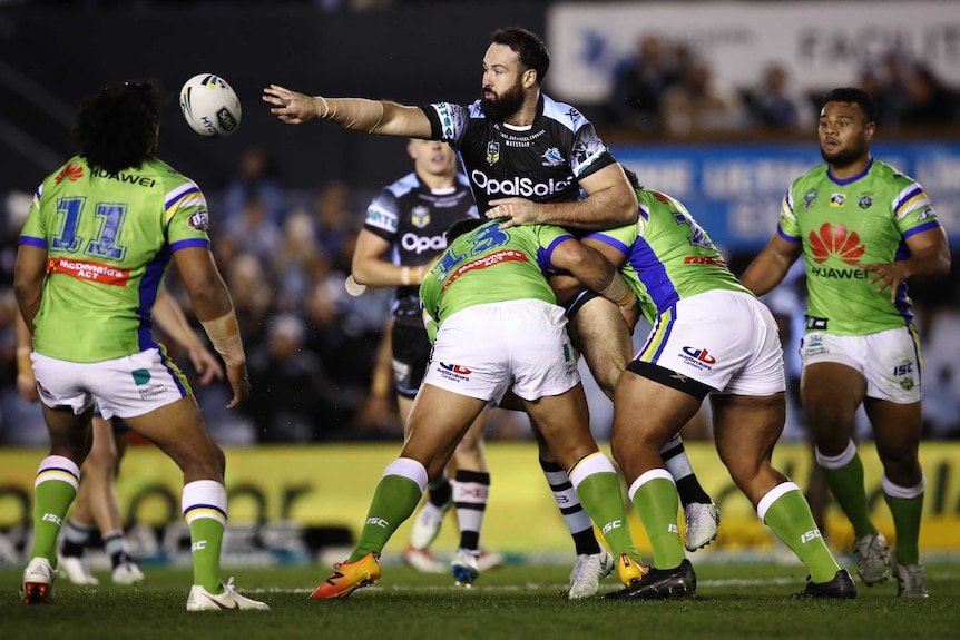 Aaron Woods gets an offload away in the tackle for the Sharks against the Raiders.