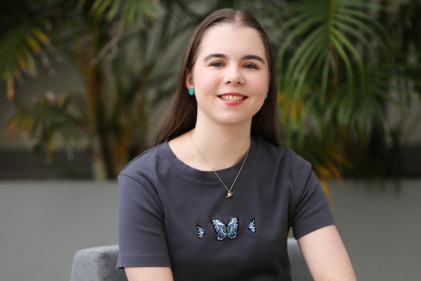 A young woman in a butterfly t-shirt smiling.