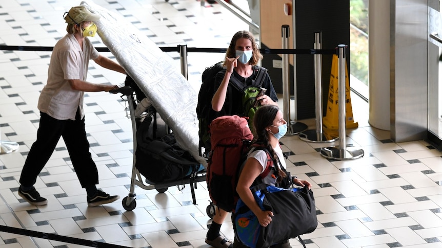 Three people walking out of an airport terminal