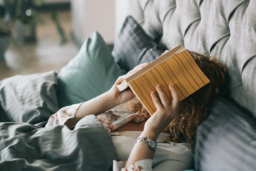 Woman covering her face with a book.
