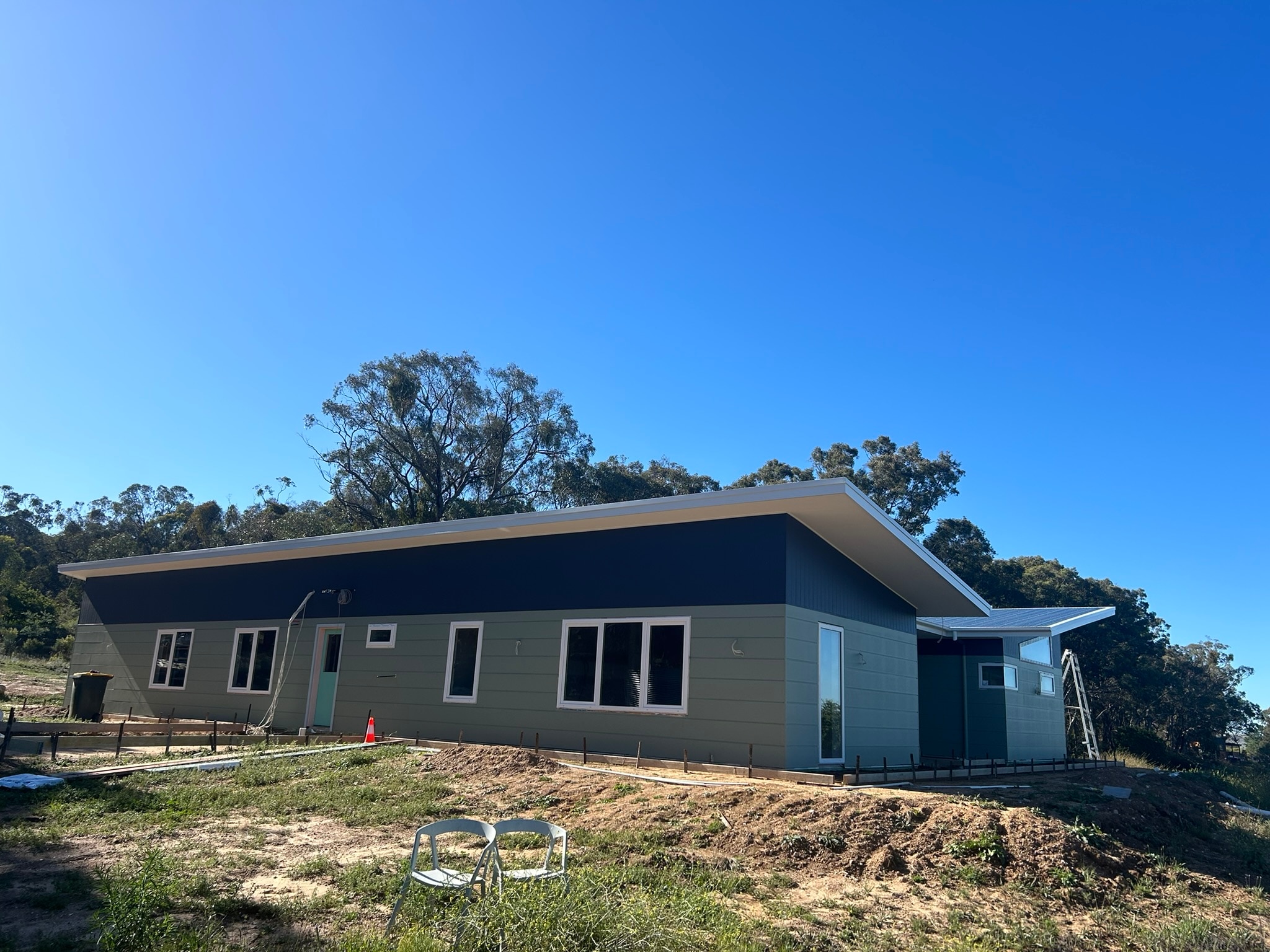 A home under construction with slanted roof panels, and light paint colours on a sunny day.