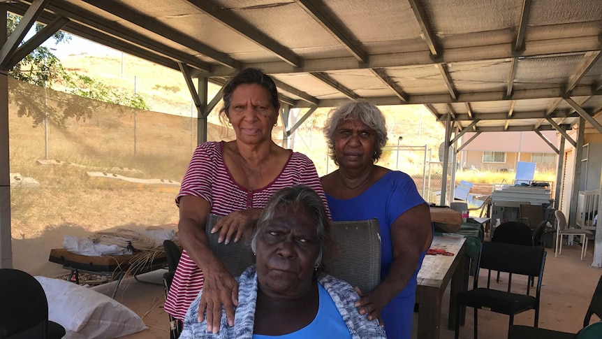 Three Aboriginal women from the Yindjibarndi tribe stand together undercover on a warm day in WA's Pilbara town of Roebourne