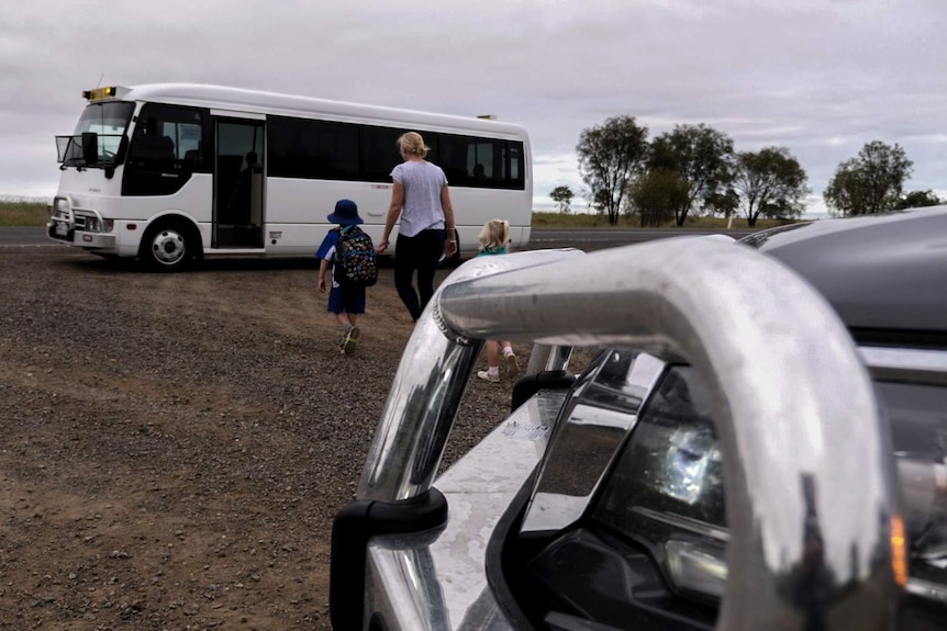 A mother and children walk from 4wd to large bus