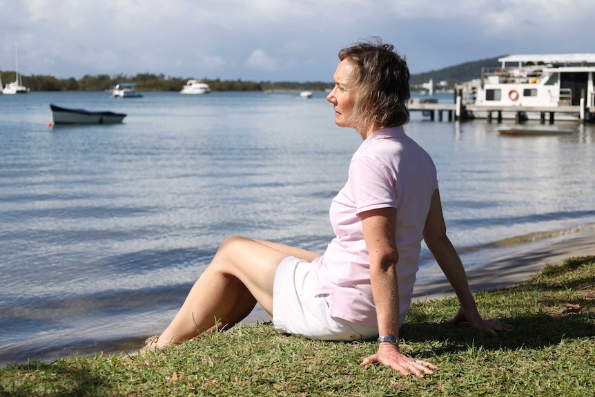 Michelle Snape sits by a river, looking at the water.