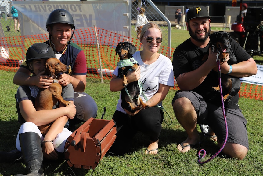 Four people standing with their dogs after receiving first, second and third in dog race.