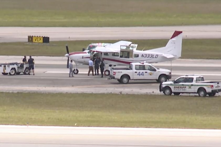 A small plane surrounded by emergency vehicles on a runway