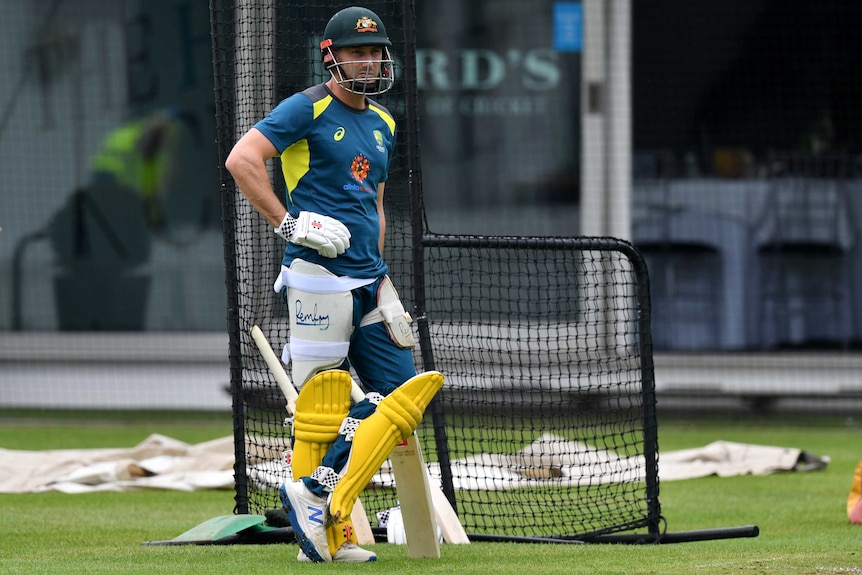 Cricketer in gear waiting to take his turn to bat in the practice nets.