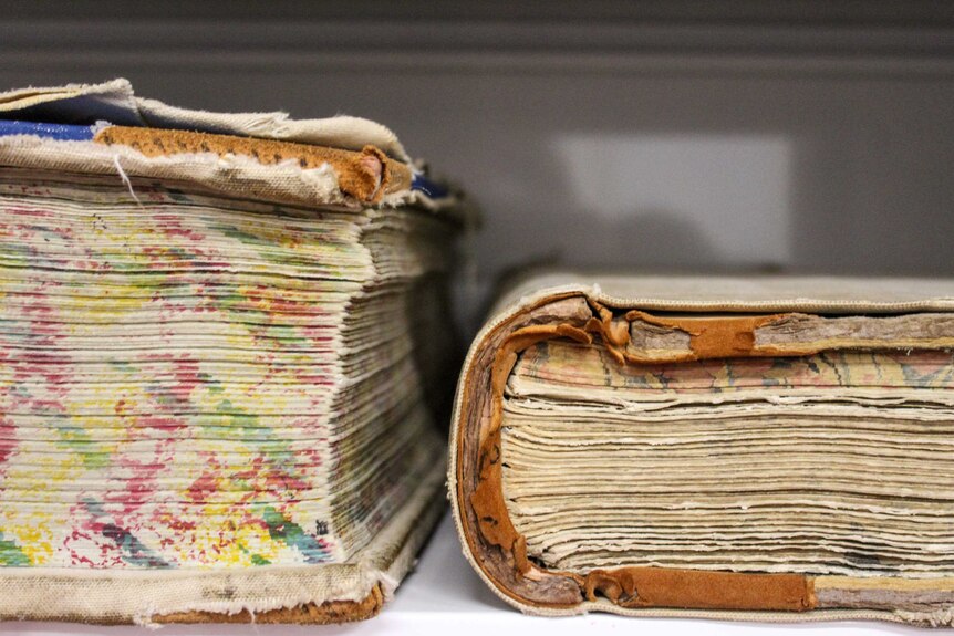 Two large, old books with pages that are worn out.