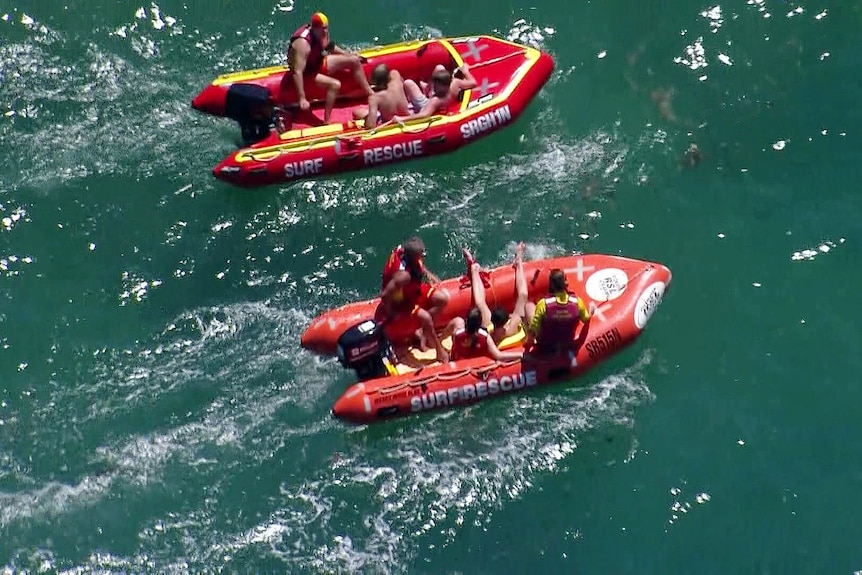 Surf lifesavers and boys in inflatable rescue boats after a cave rescue in sydney