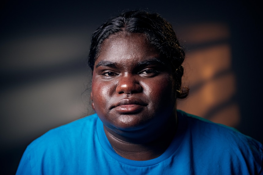 a young aboriginal woman wearing blue in a dark room