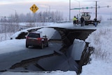 A car is stopped on road that has dropped some distance below the next section.