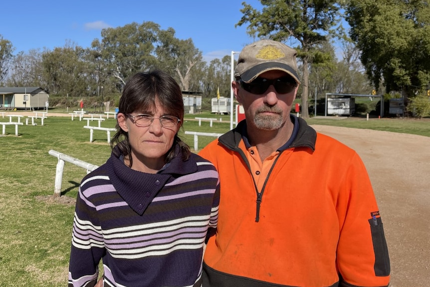 Two middle-aged people standing in front of an empty caravan park.