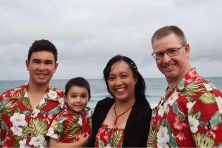 Everly Wyss and husband Glenn (right) and two other family members stand on a beach with the ocean behind them.