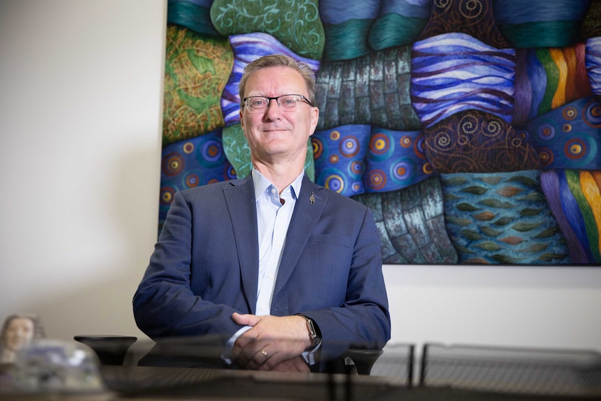 A man sits in an office smiling.