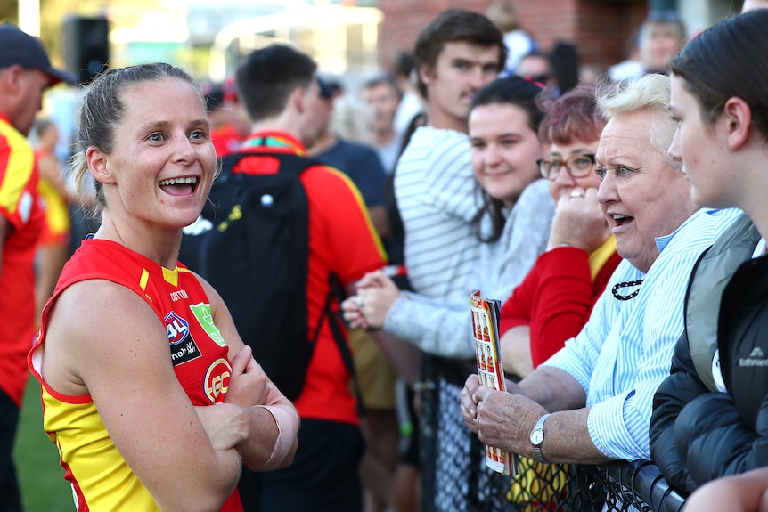 Kate Surman of the Gold Coast Suns talks to supporters on the boundary line 