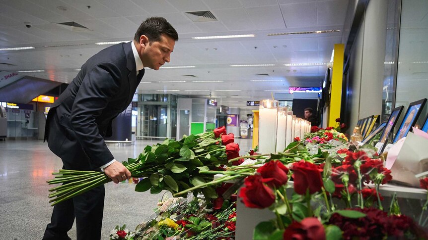 Ukrainian President Volodymyr Zelenskiy lays flowers at a memorial for Ukrainian Airlines flight crew.